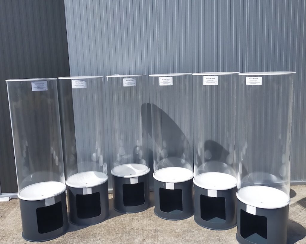 Cuvettes en plexiglas transparent sur montants cylindriques gris foncé, en rangée, utilisées comme aquariums ou présentoirs, avec étiquettes en haut. aquarium plexiglas sur mesure