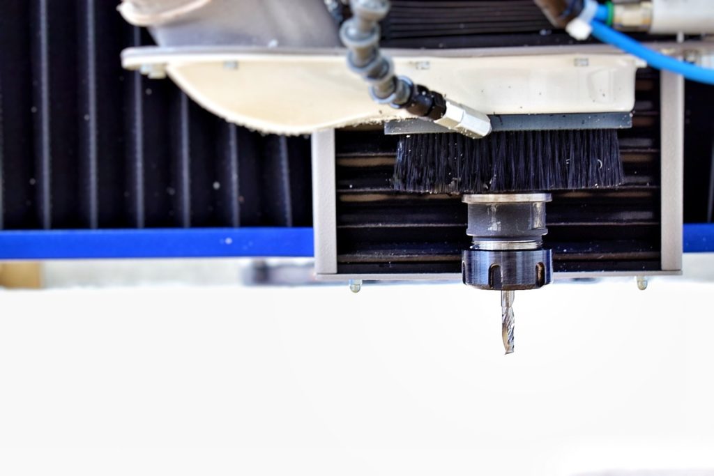 Différence entre pmma coulé et extrudé : machine de fraisage/usinage du plexiglass en cours, avec tête de coupe et consommables visibles.