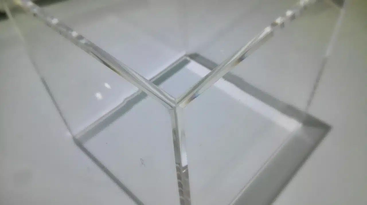 Trois surfaces transparentes de plastiques assemblées en carène lumineuse, montrant leurs joints angulaires et les reflets brillants. Plastiques résistants aux produits chimiques.