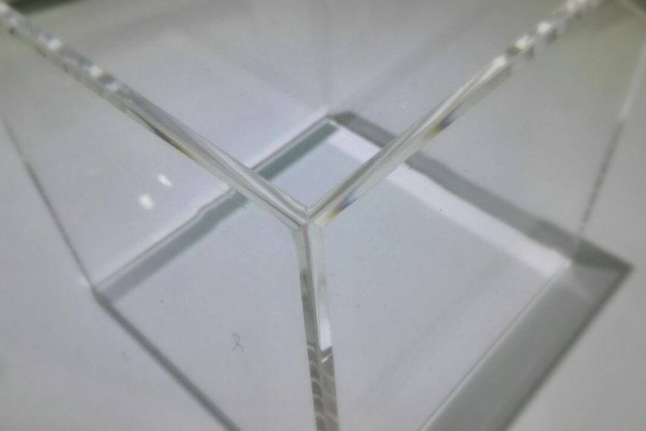 Vitrine exposition figurine en verre clair avec angles nets et reflets lumineux, mise en avant d’un socle compartimenté.