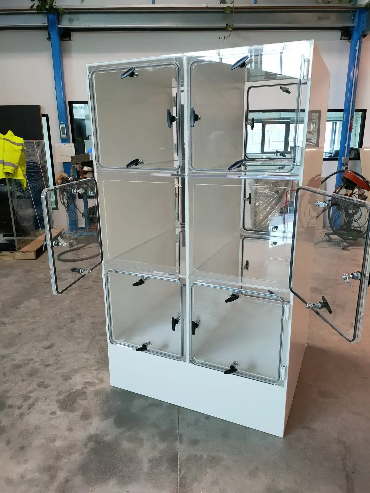 Vitrine en plexiglas empilable à 6 compartiments avec portes transparentes et poignées noires, ouverte sur les côtés pour exposition ou ventilation. Vitrine en plexiglas empilable à 6 compartiments avec portes transparentes et poignées noires, ouverte sur les côtés pour exposition ou ventilation.
