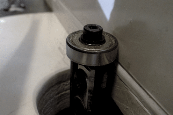 Rondelle et mécanisme de coupe autour d’un trou dans un plateau, outil de fixation noir et métallique près du mur.